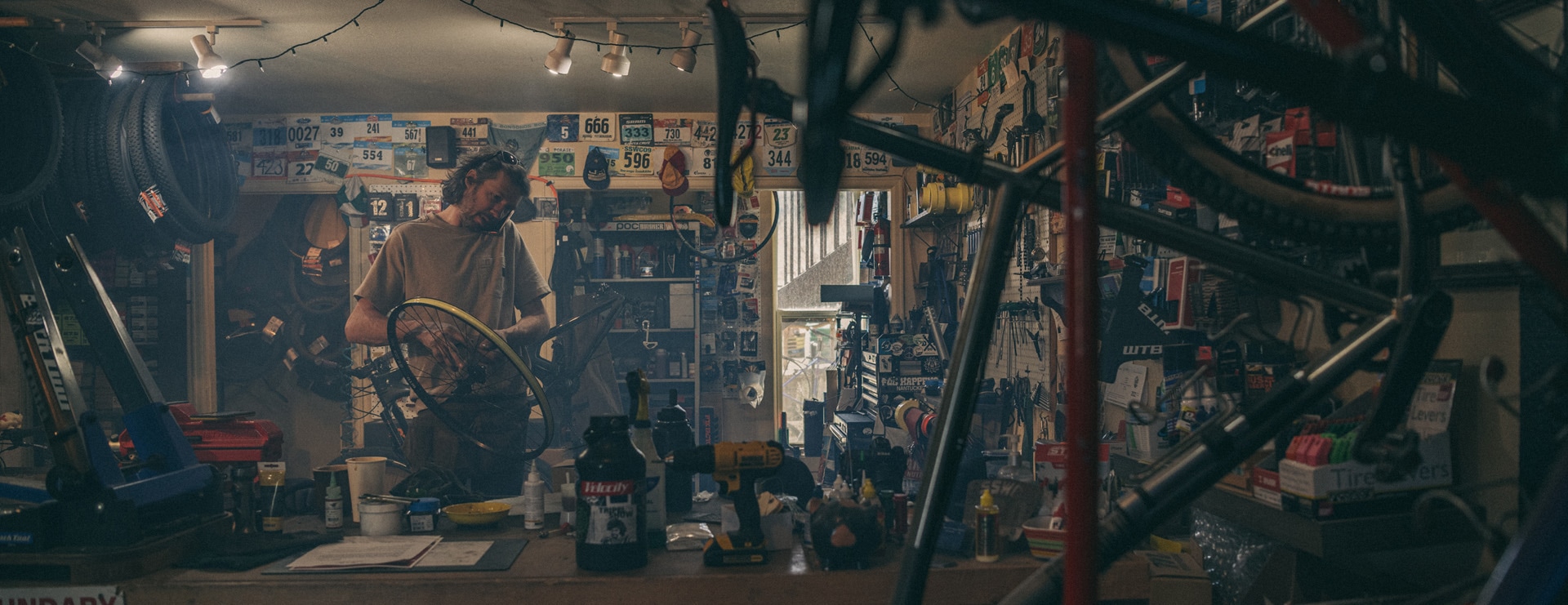 Nathan Miller in the background working on a bike with bikes hanging in the foreground.