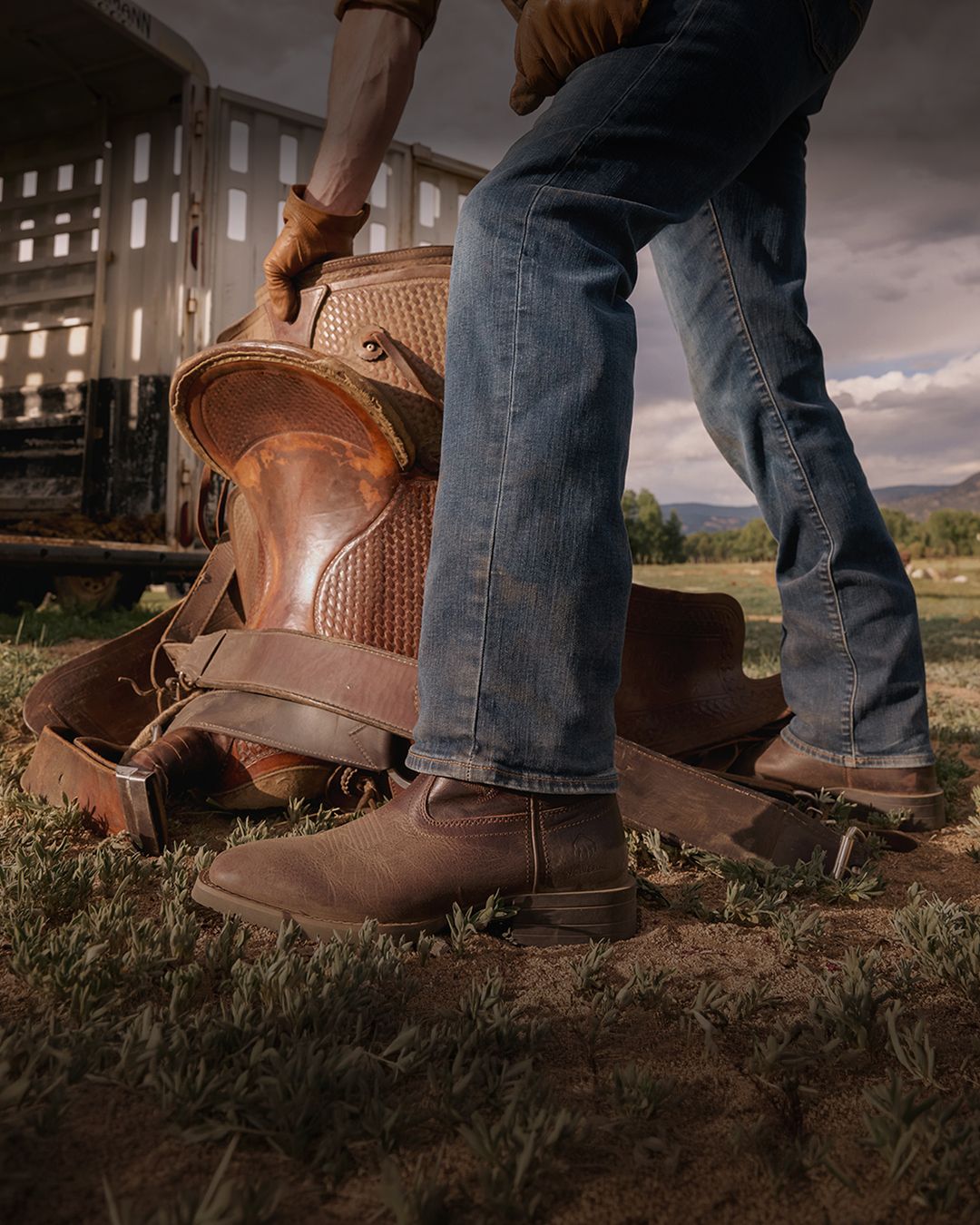 Brown boots standing beside a horse saddle.