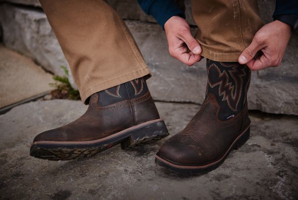 Pulling pant leg over brown wellington boot.