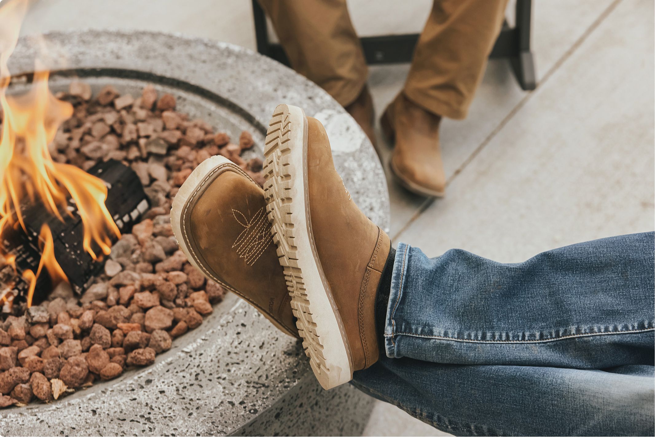 Clogs resting on the edge of a campfire.