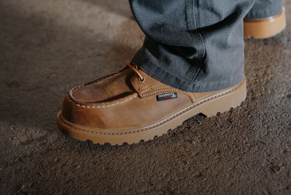 Tan boots walking on a concrete floor.