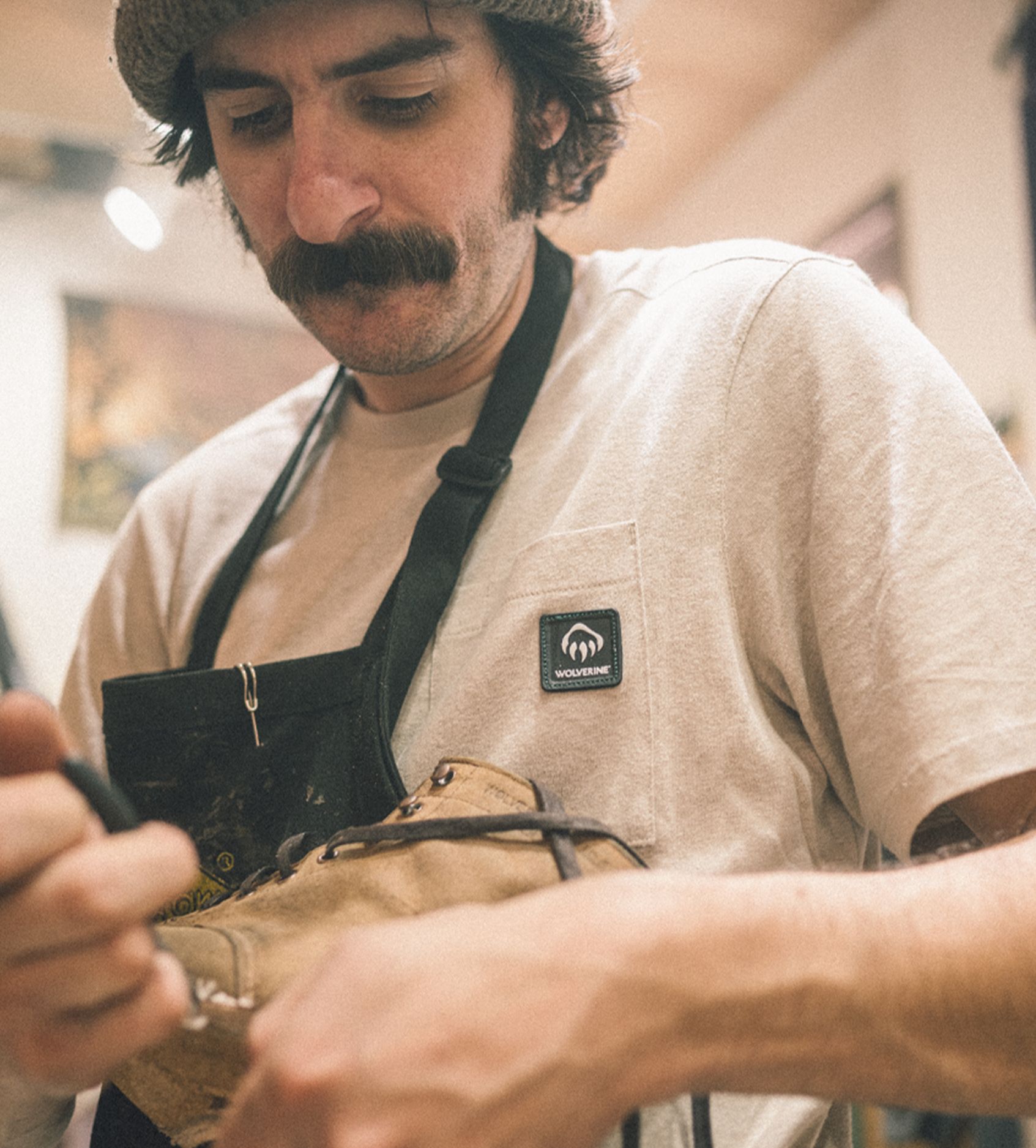 a man with a mustache and a hat looking at a shoe