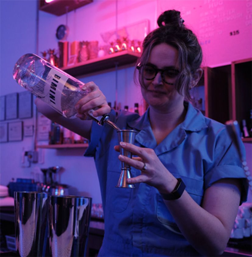 a woman pouring a drink into a cup