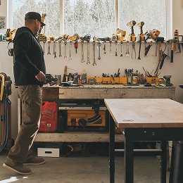 Worker in a garage workshop walking past a workbench.