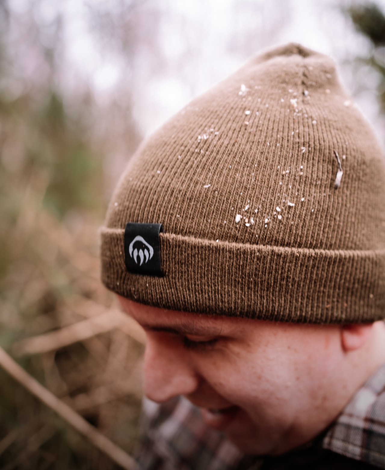 A worker in a beanie and flannel, and a close-up of leather work gloves.