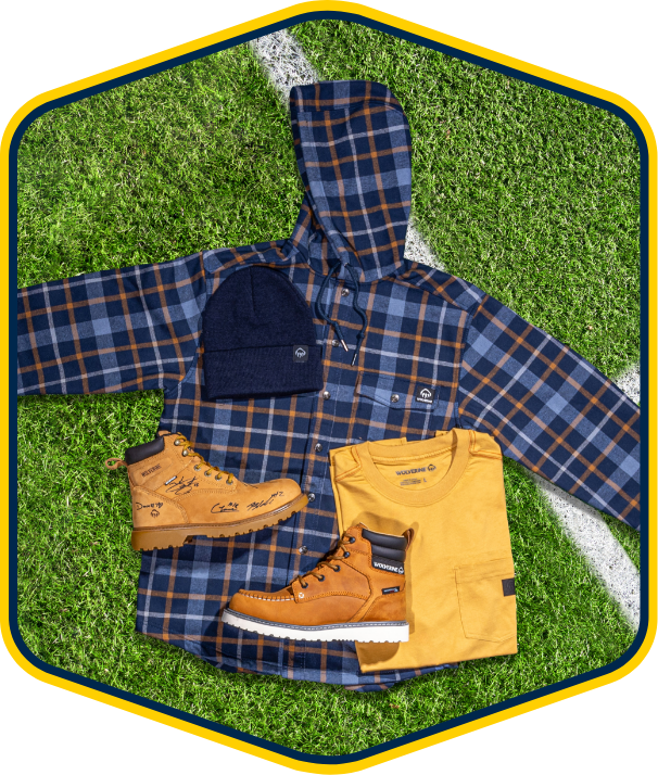 a blue and orange plaid shirt and boots on a green grass field