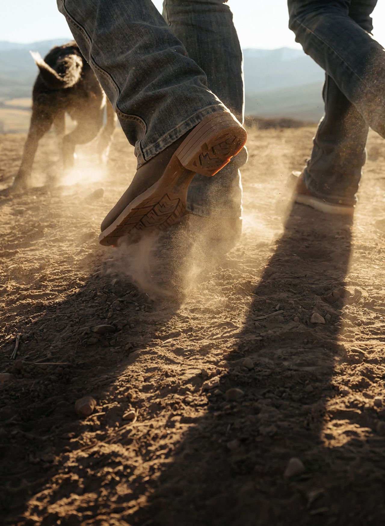 Multiple men wearing western wolverine boots walking on dirt.