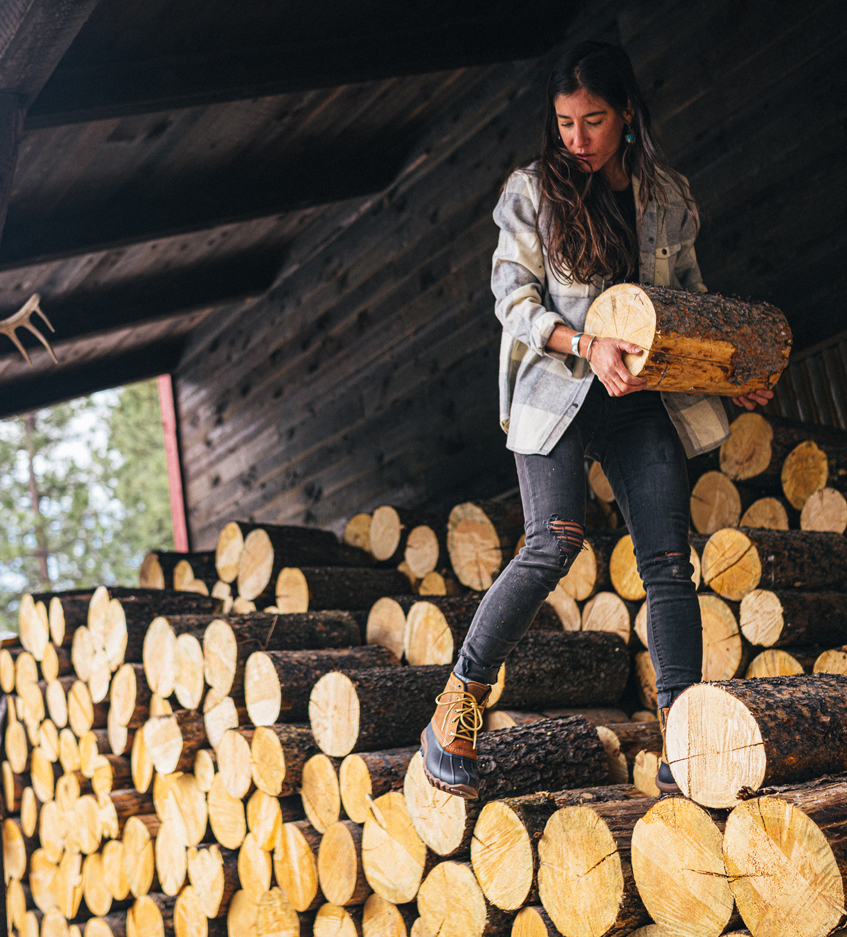 Jessie Lewis standing on a pile of logs.