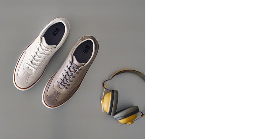 Wolverine BLVD Court sneakers in a variety of colors beside a pair of noise-canceling headphones.