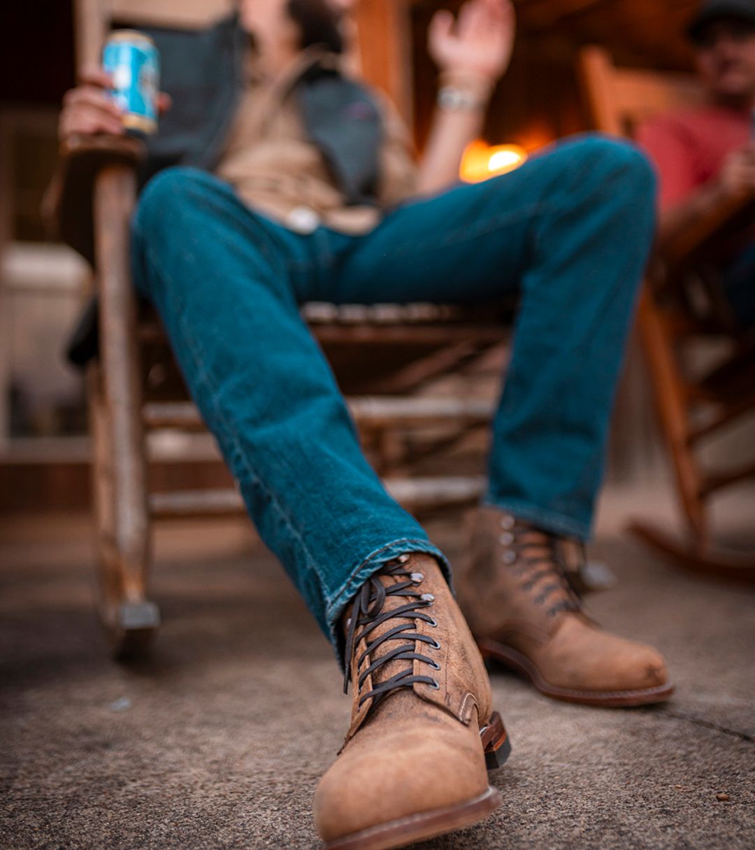 Sitting in a rocking chair wearing blue jeans and waxy brown 1000 Mile boots.