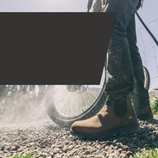 Person wearing Wolverine boots power-washing a bicycle wheel.