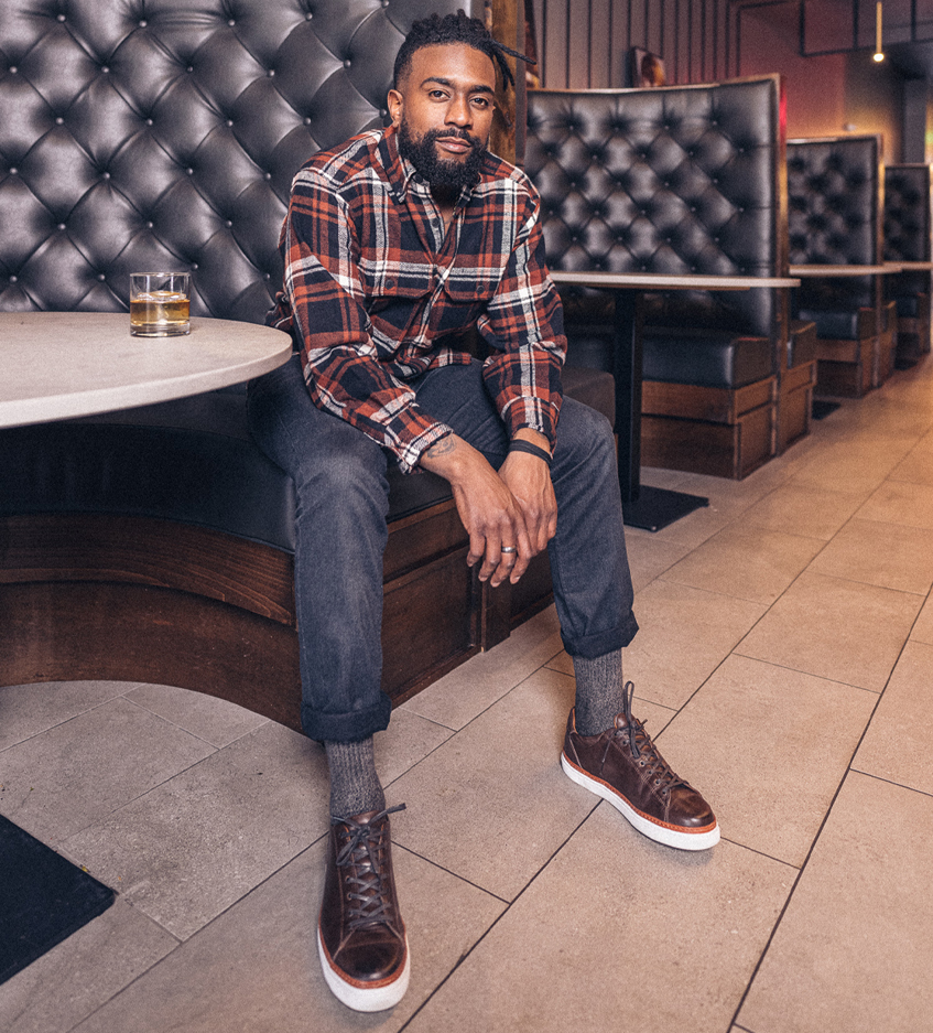 Chase Bardole sitting on the edge of a booth at his bar.