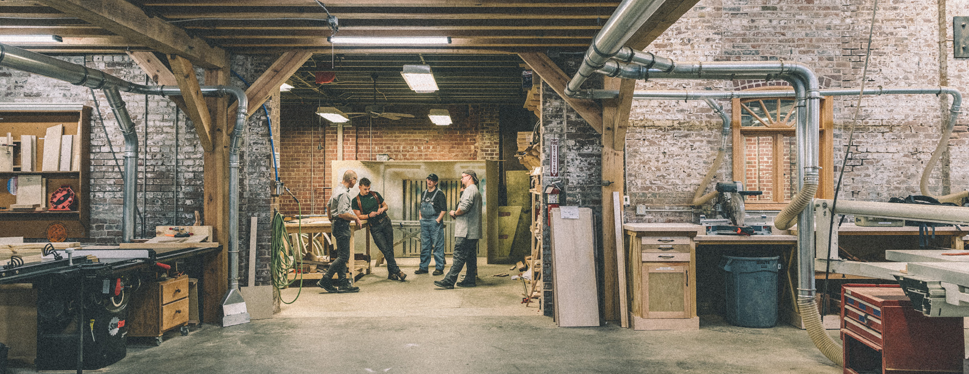 A medium range shot of Markus and some of his apprentices in the shop.