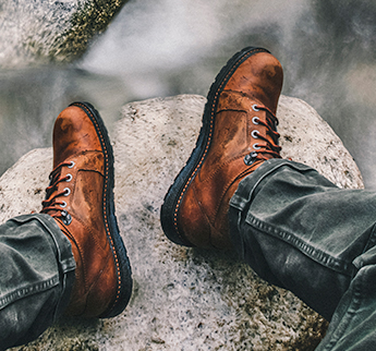 Person wearing boots sitting on a cliff.