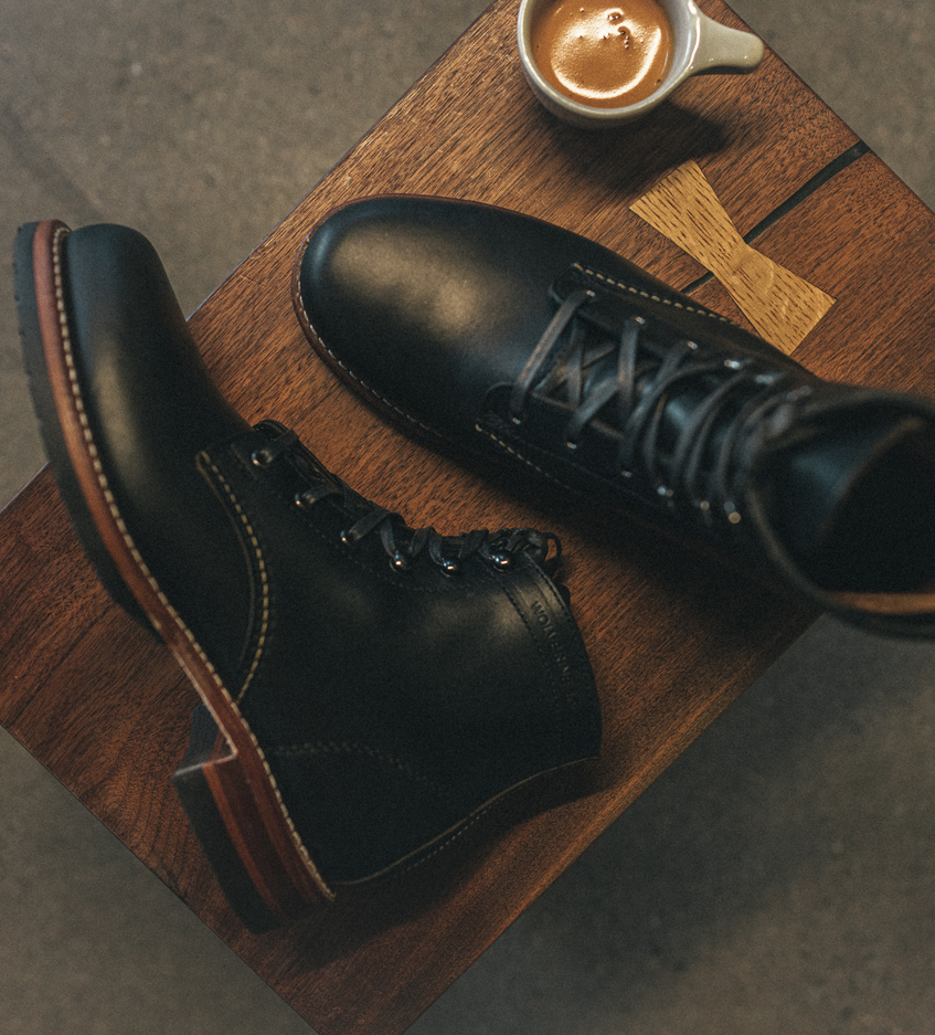 A pair of Wolverine boots resting on a tiny coffee table.