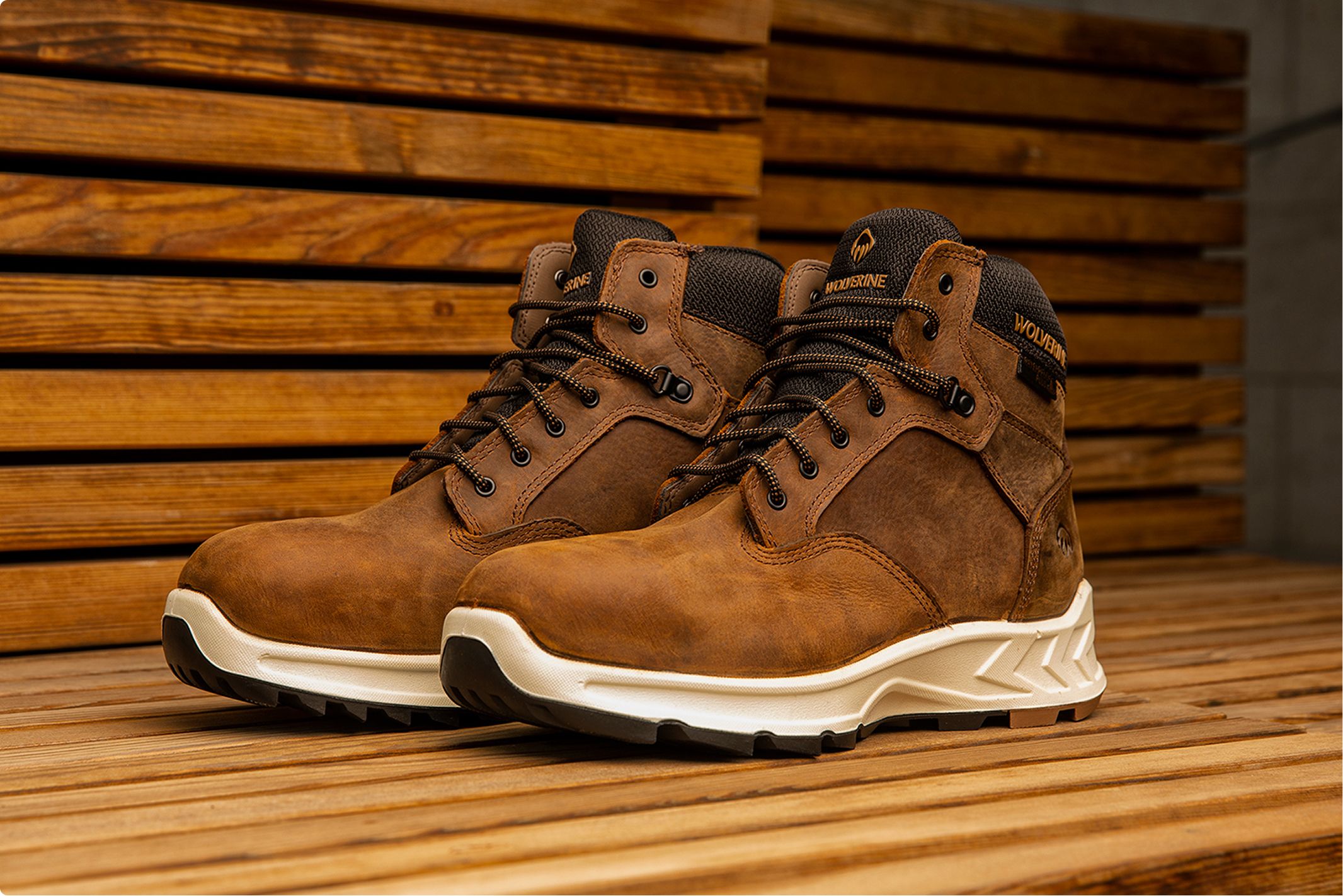 Pair of brown boots on a slatted wood bench.