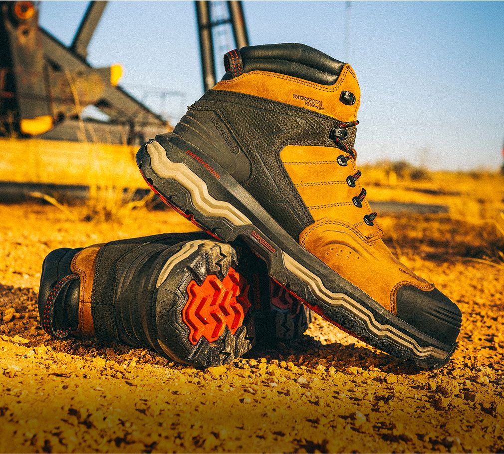 Boots on arid ground beside an oil derick.