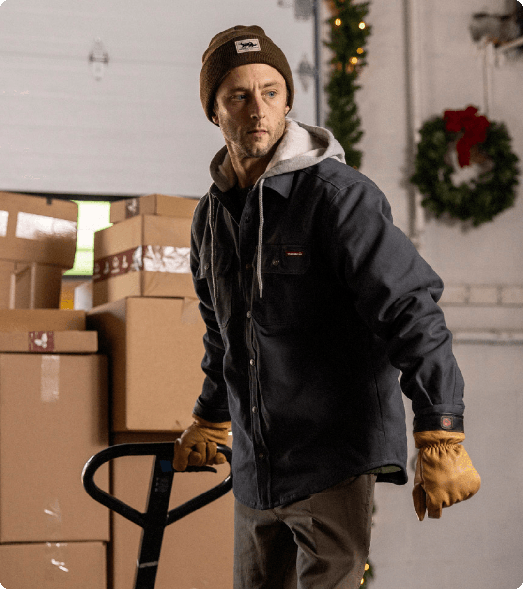 Pulling a handcart of boxes wearing a Wolverine jacket and beanie.
