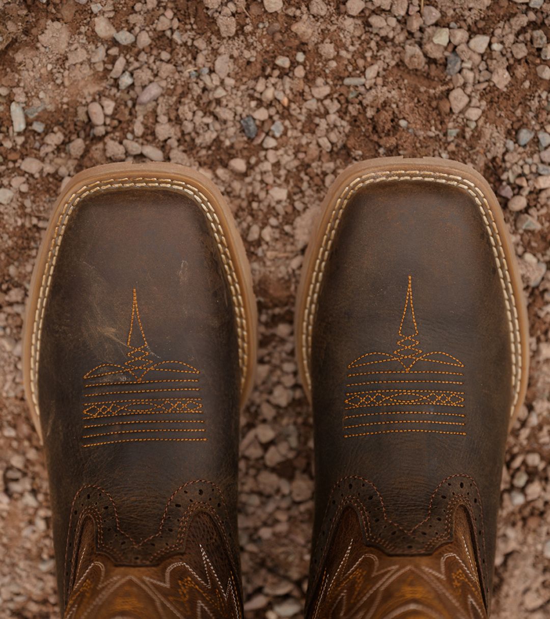 A pair of Sudan brown boots standing on dirt.