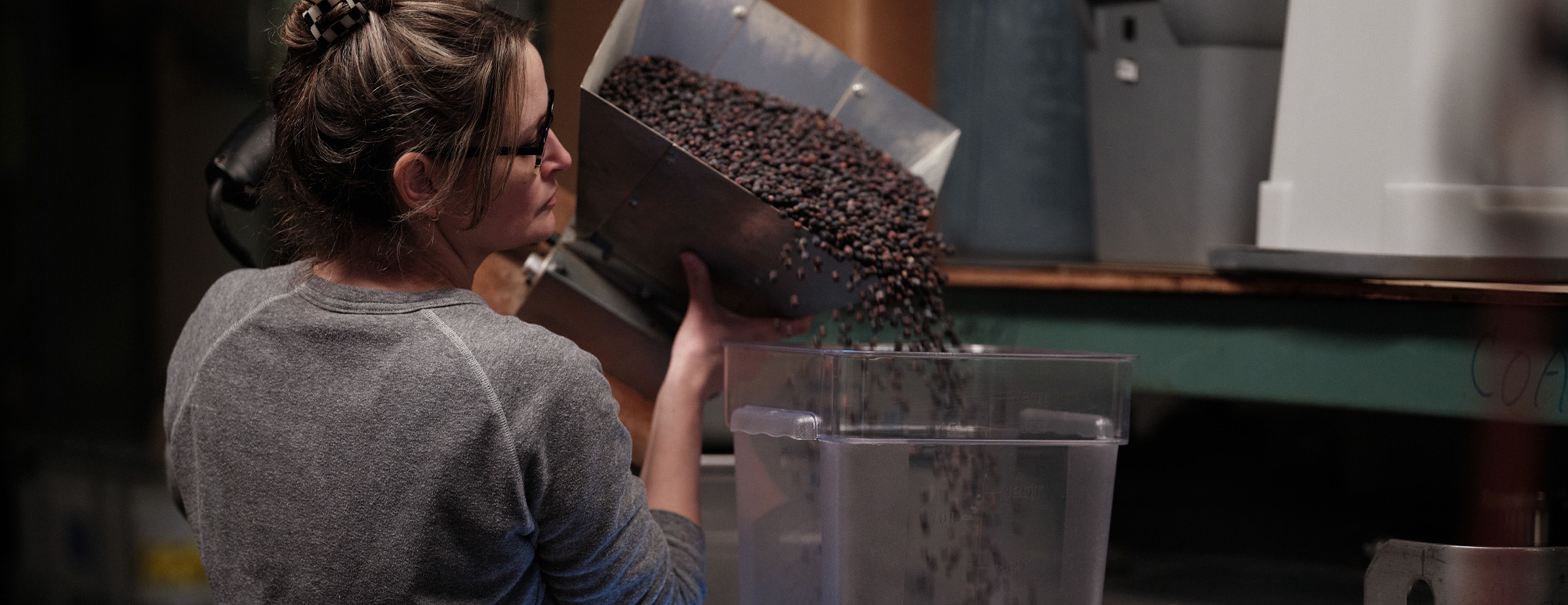a woman pouring beans into a container
