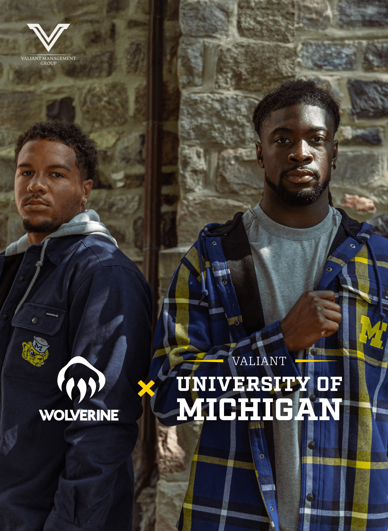 Two people against a stone wall wearing apparrel from the Wolverine x Valiant Management Group University of Michigan collection.