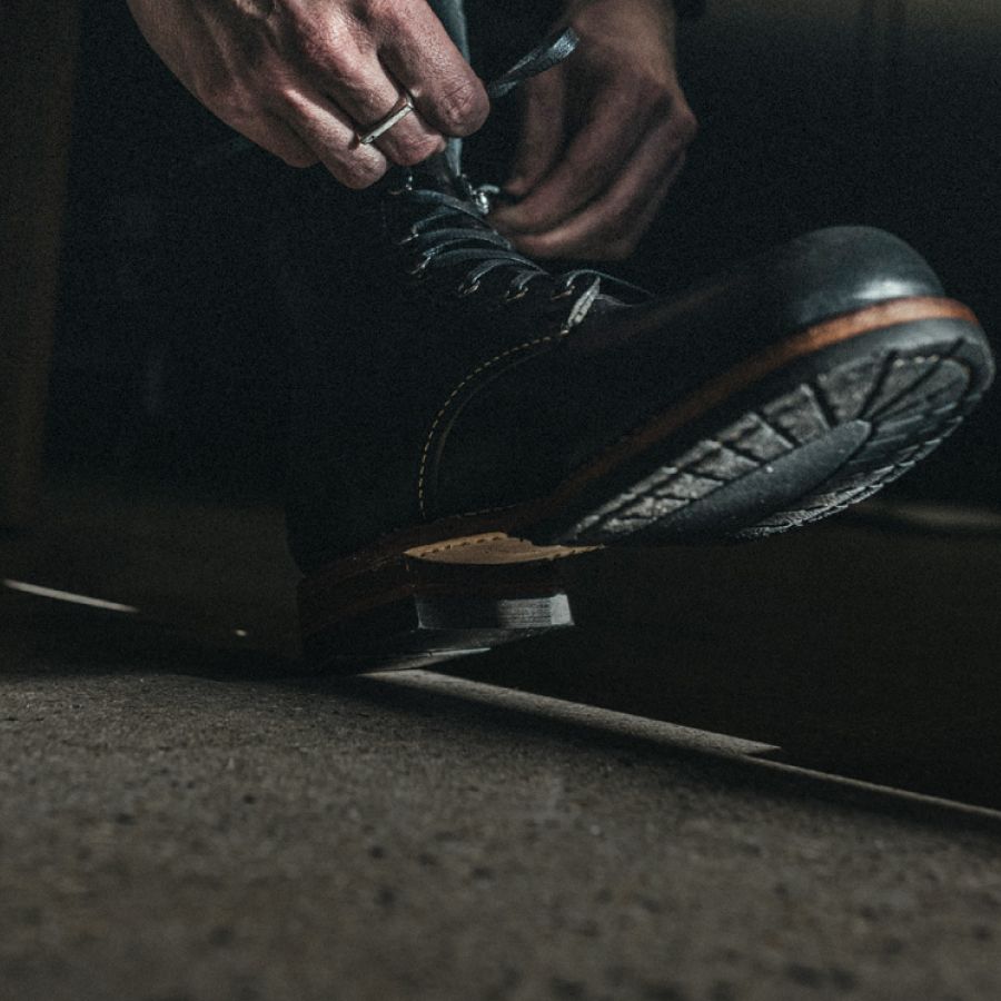 Tying laces on a black leather boot.