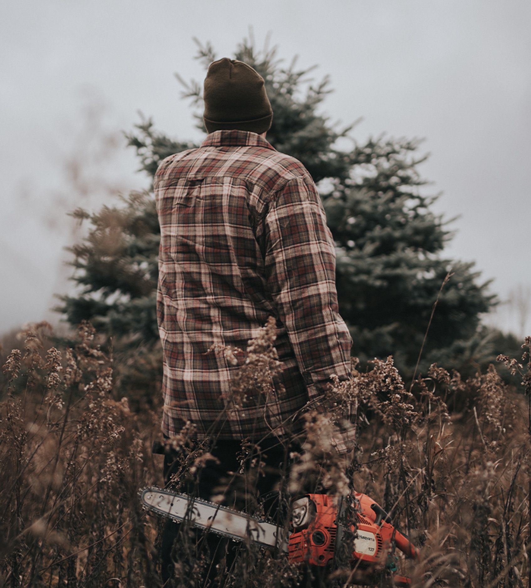 a man standing in a field with a chainsaw