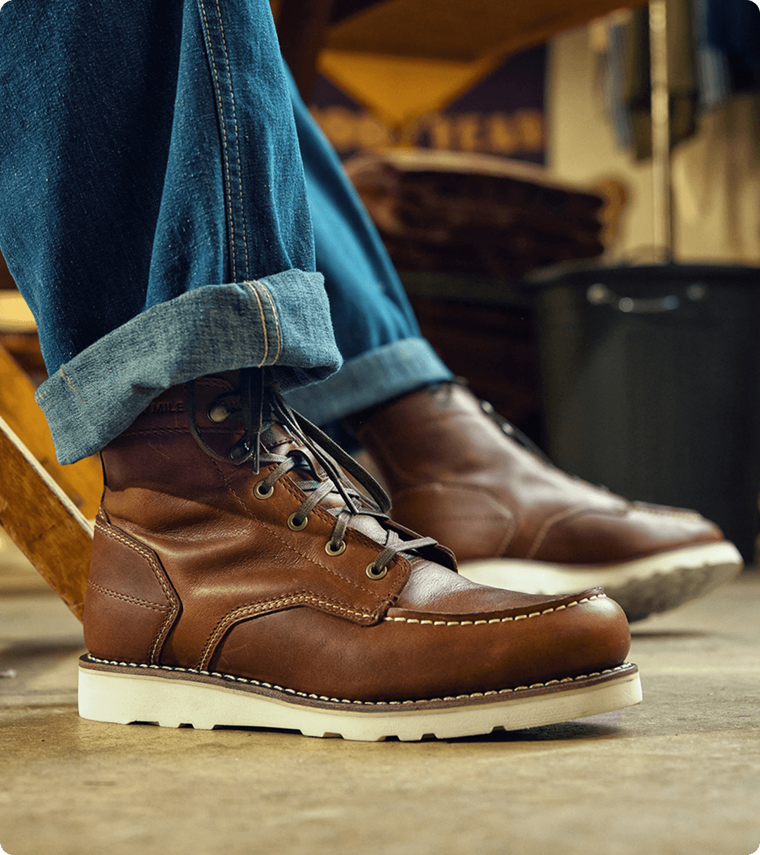 Sitting in a chair wearing light blue jeans and brown boots.