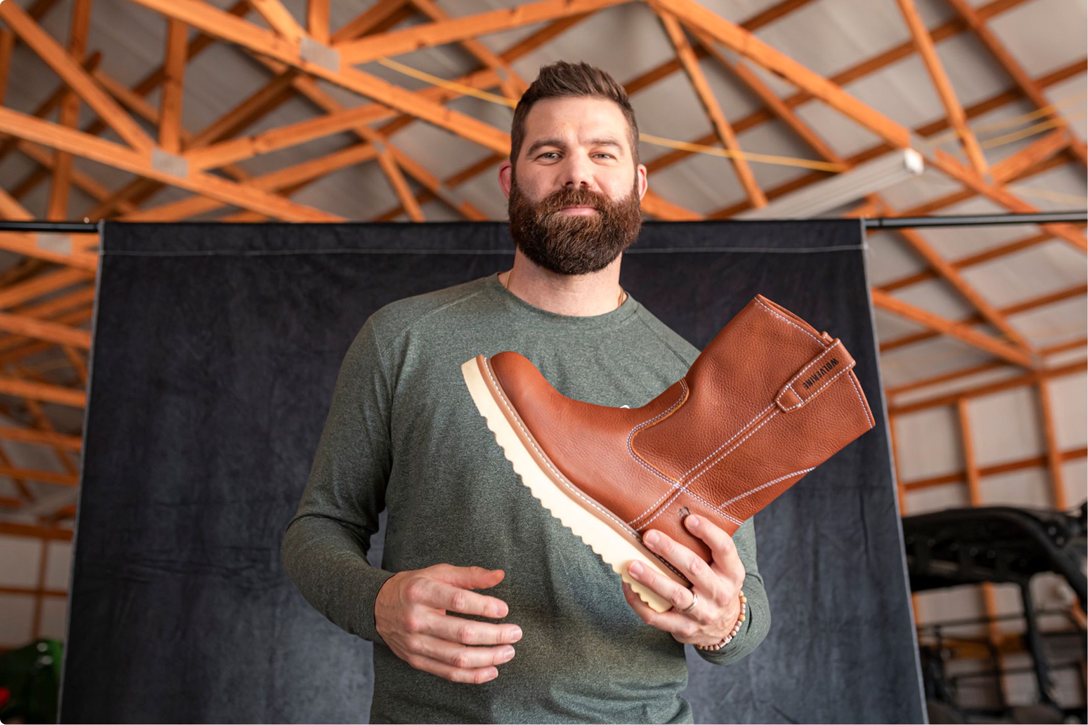 Holding a boot by the heel in a barn.