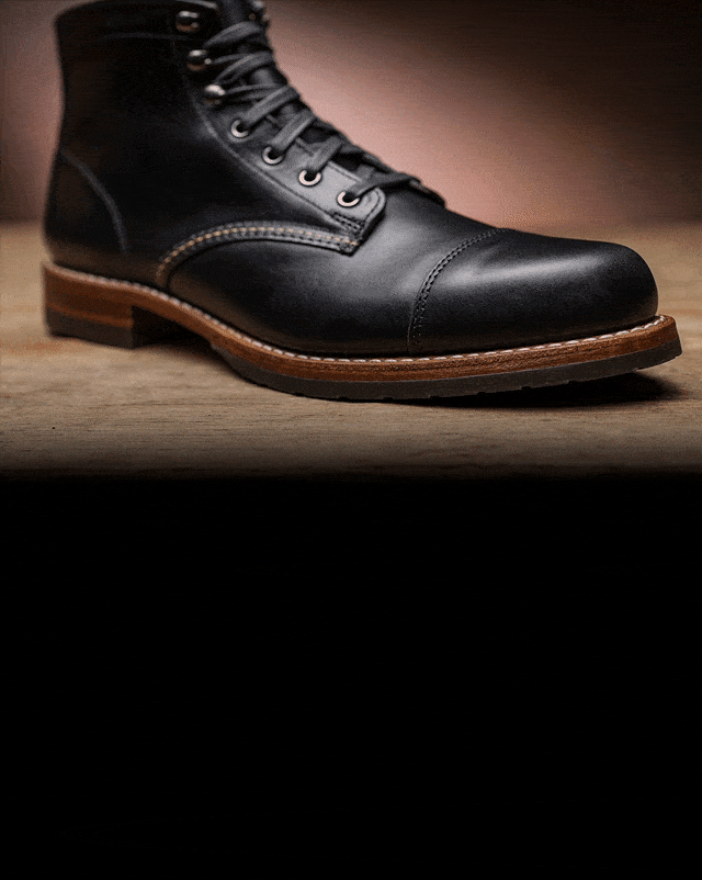 A black leather boot on a hard wooden surface.