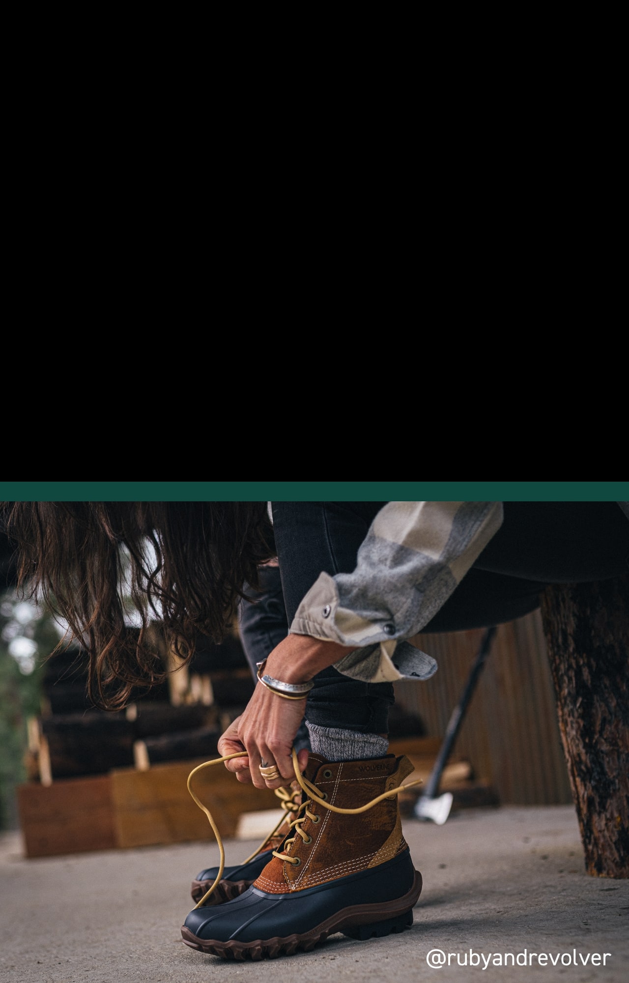 Person tying her Torrent boots, sitting in a rustic setting.