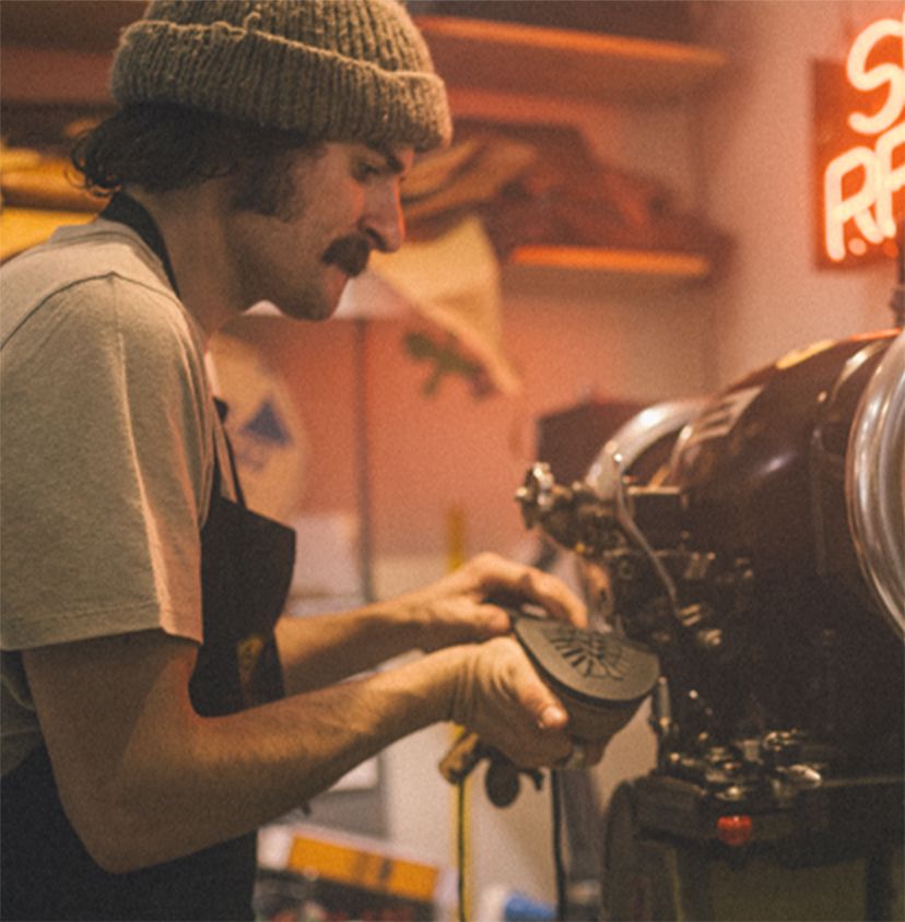 a man wearing a beanie working on a shoe at a machine
